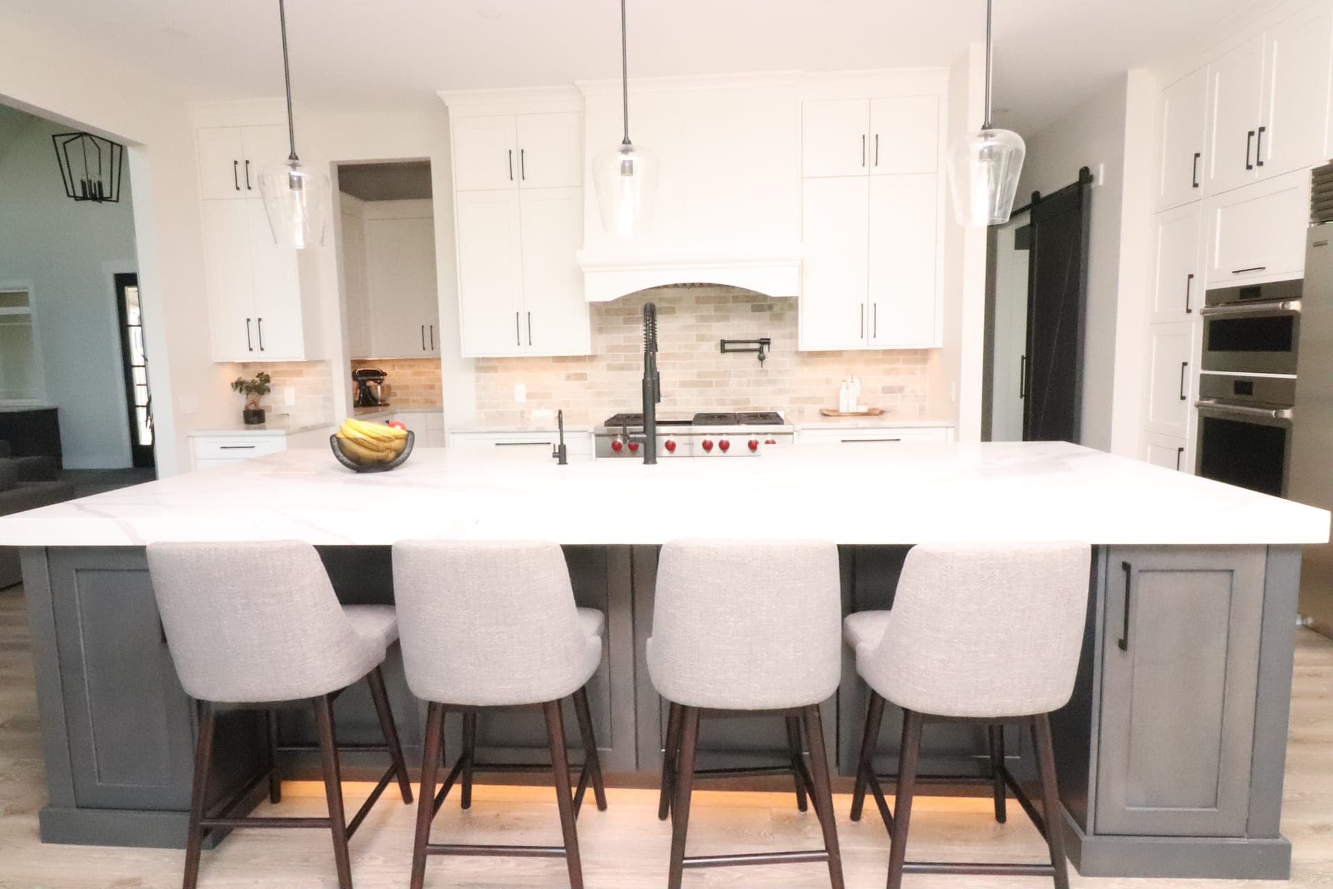 Gordon residence — white kitchen from bar seating angle with pendants and under-cabinet lighting
